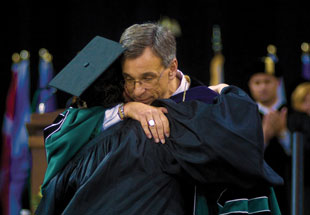 Image of President Emeritus James Votruba and student hugging at commencement
