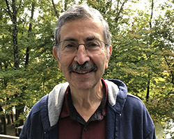Dr. Alan Cohen smiling in front of a forest
