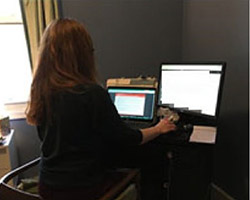 Woman sitting in front of a computer with two screens