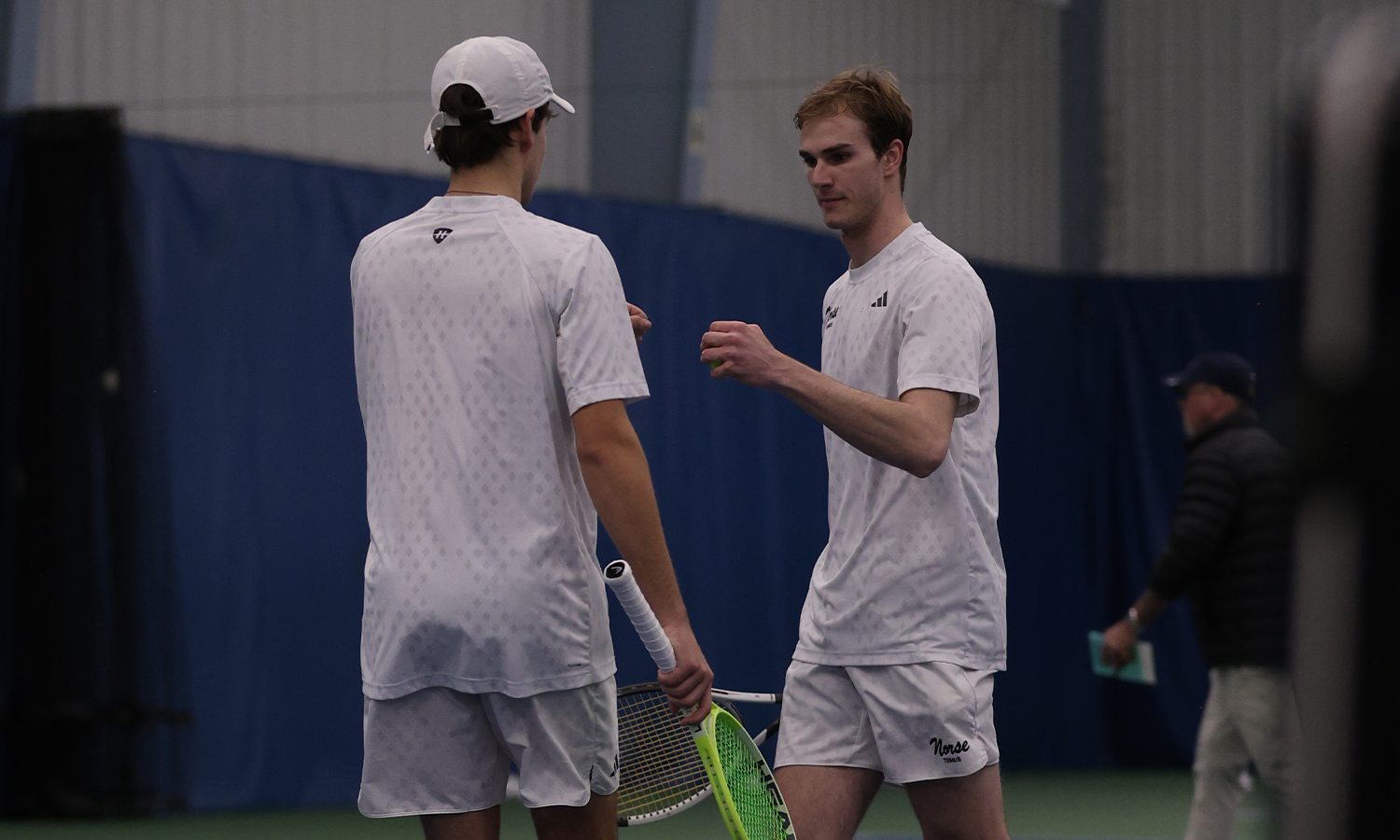 Two men's tennis players giving each other a fist bump
